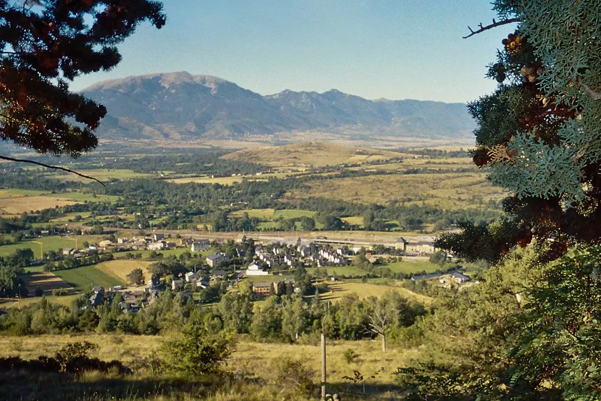 Vue panoramique sur la vallée et le village d'Enveitg entouré de montagnes.