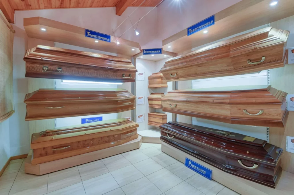 Exposition de cercueils en bois dans une salle de vente de pompes funèbres.