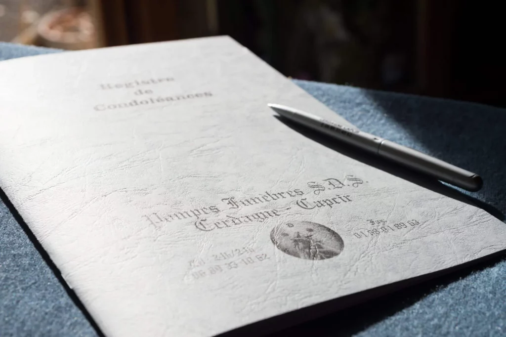 Registre de condoléances en papier des pompes funèbres pose sur une table.