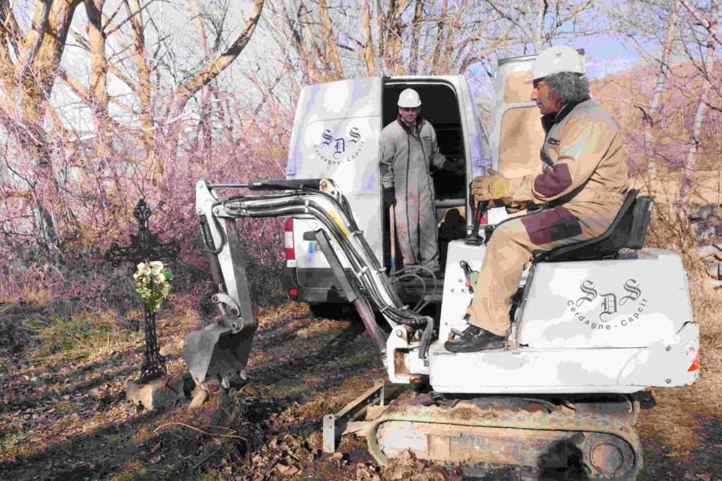 Travaux de marbrerie et terrassement dans un cimetière avec mini-pelle.