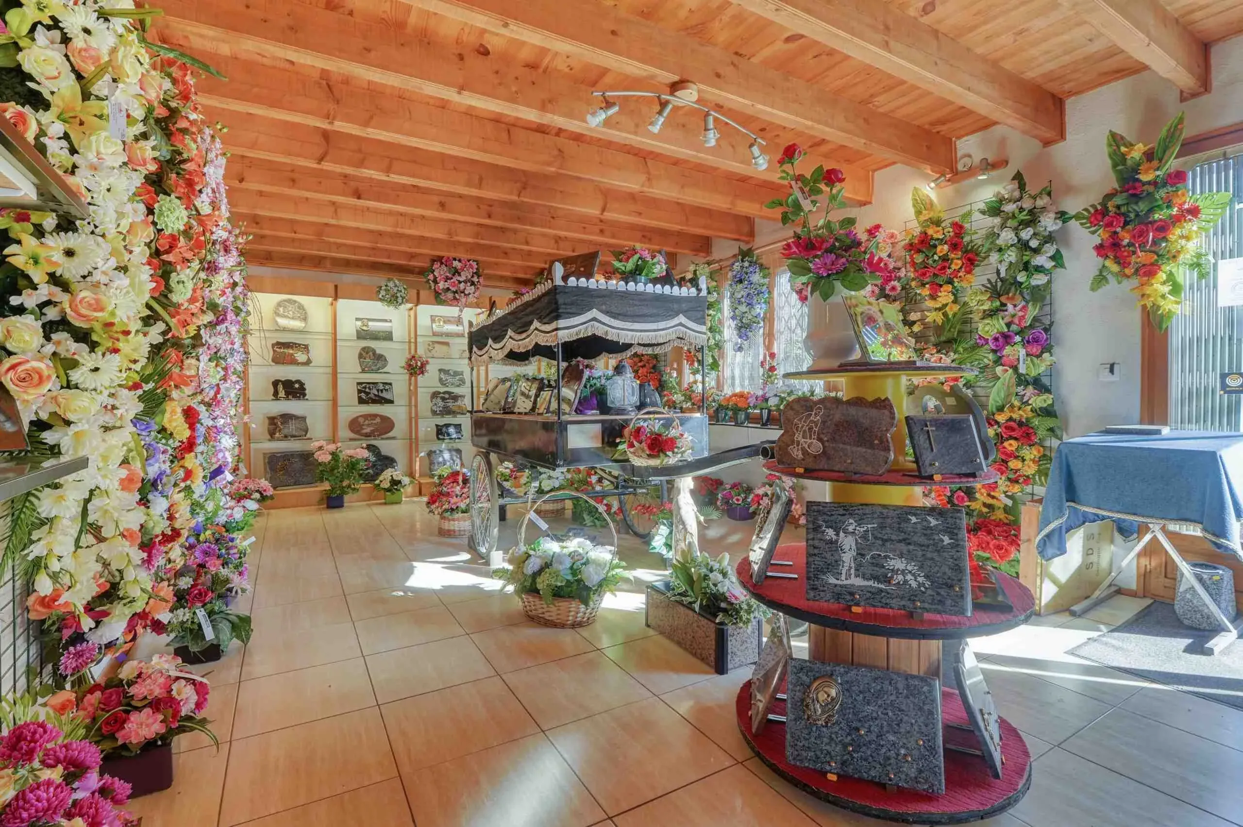 Magasin d'articles funéraires avec plaques souvenir et fleurs artificielles.