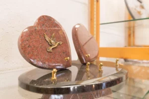 Plaques funéraires en granit rose en forme de cœur ornées d'une colombe.